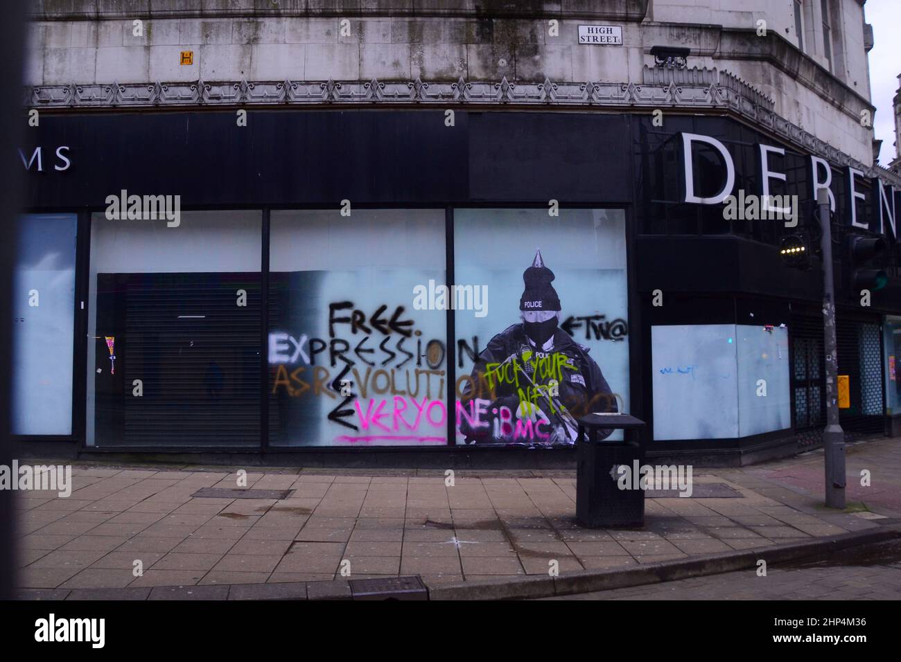 Manchester, UK, 18th February, 2022.  A humorous mural featuring UK Prime Minister Boris Johnson on the old Debenhams store in central Manchester, UK, has been vandalised twice so far with graffiti. Produced by 'Foka Wolf', a street artist, the mural has Boris Johnson's head, wearing a party hat, on top of an image of an armed police officer. There is a police investigation into parties at 10 Downing Street during the Covid-19 lockdowns. The artist has mentioned what he sees as the Government's 'double standards'. Credit: Terry Waller/Alamy Live News Stock Photo