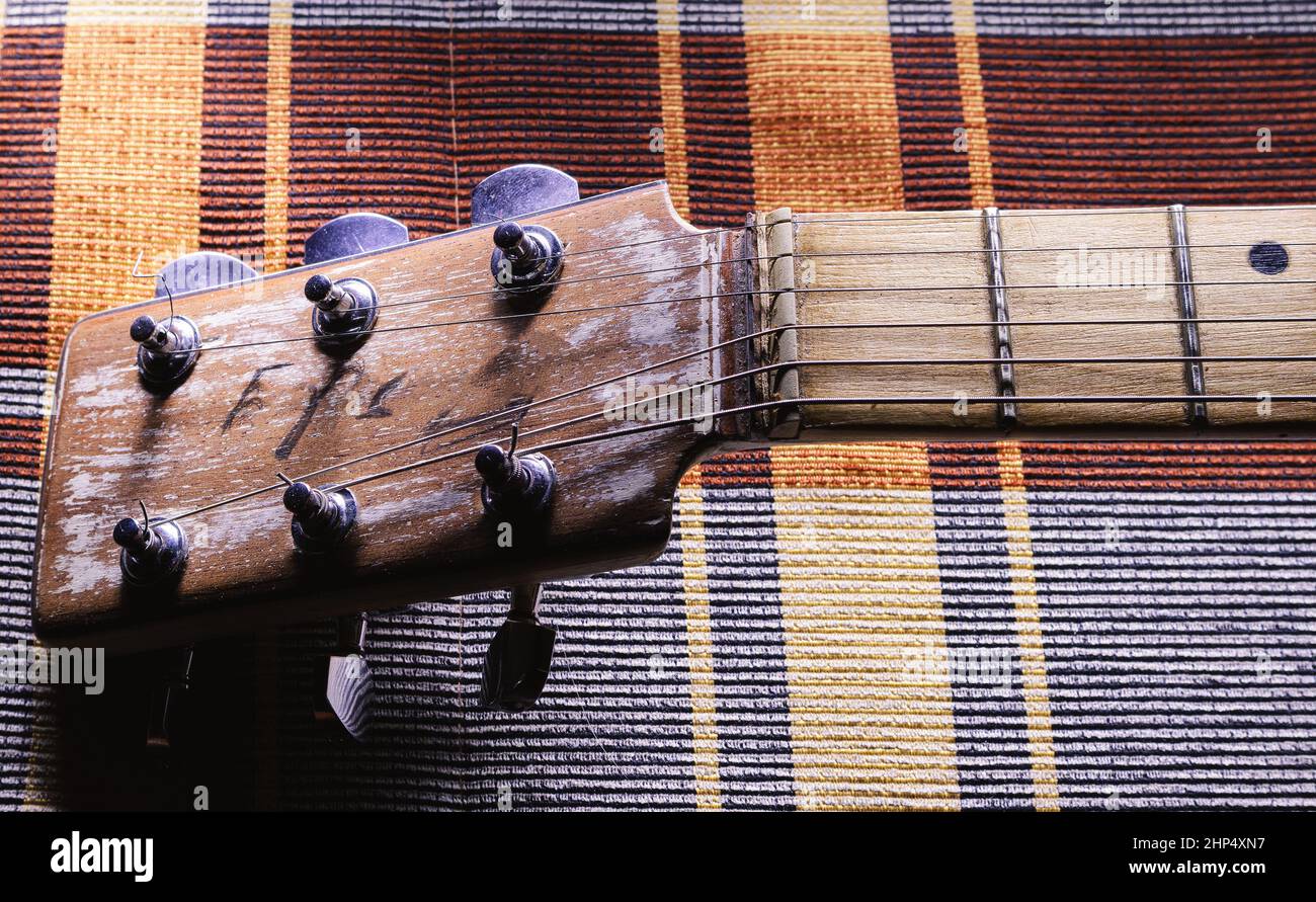 Details of an old vintage style acoustic guitar, view on head with strings, nut and part of a neck. Stock Photo