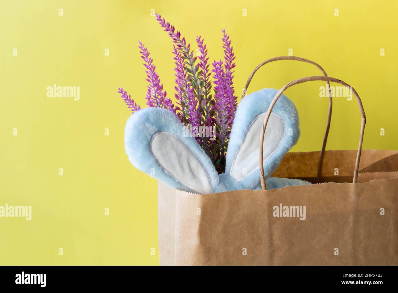 A bandage, blue rabbit ears and an artificial lavender branch stick out of the package. Easter greeting card design. Space for text. Stock Photo