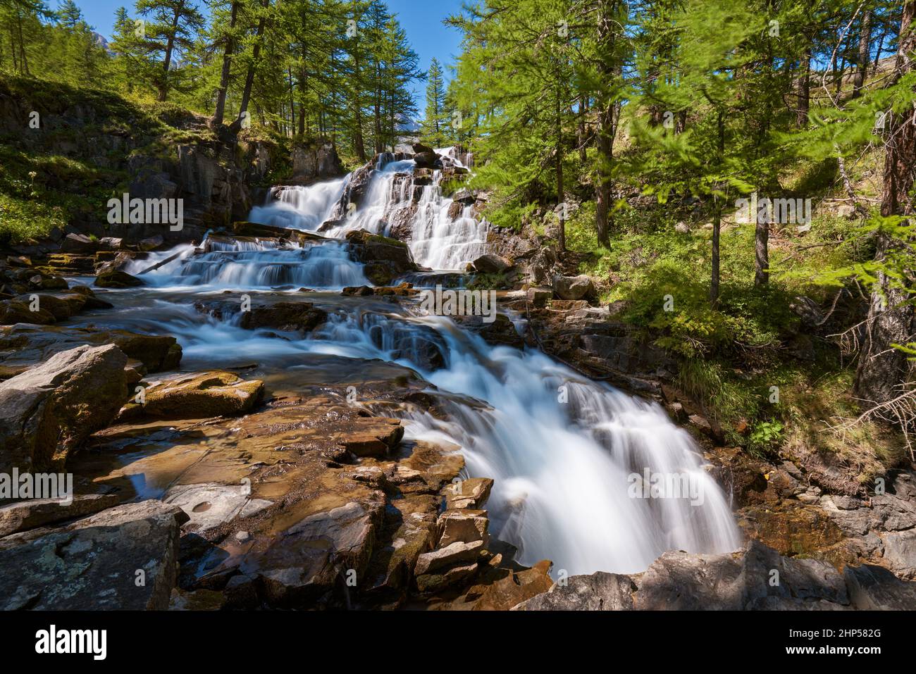 Fontcouverte Waterfall in the Claree Valley surrounded by larch trees in summer. Vallée de la Clarée in Hautes Alpes (Cerces Massif), Alps, France Stock Photo