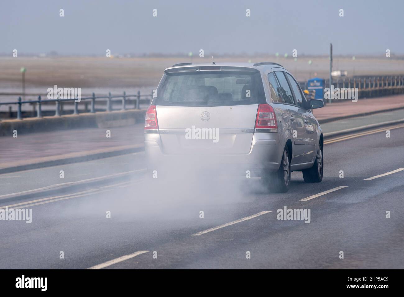 Old car with very smoky exhaust driving on the seafront road at Southend on Sea, Essex, UK. Polluting vehicle gas emissions Stock Photo