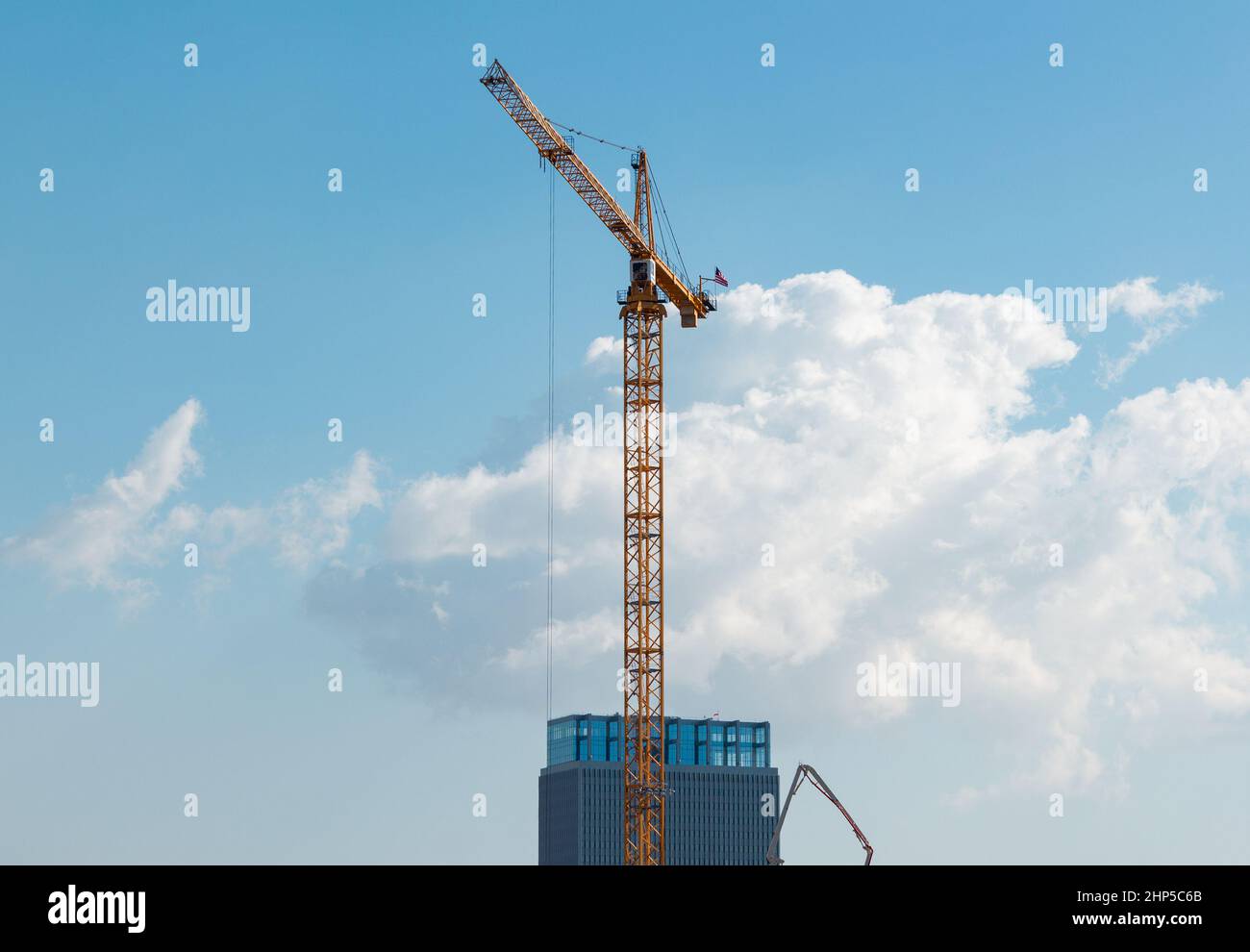 Another downtown  Los Angeles skyscraper is being built with the help of a very tall crane. The crane hovers over the building and makes it look small Stock Photo