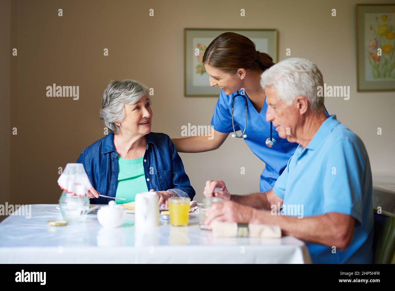 How are we doing this morning. Shot of two residents and a nurse at a retirement home. Stock Photo