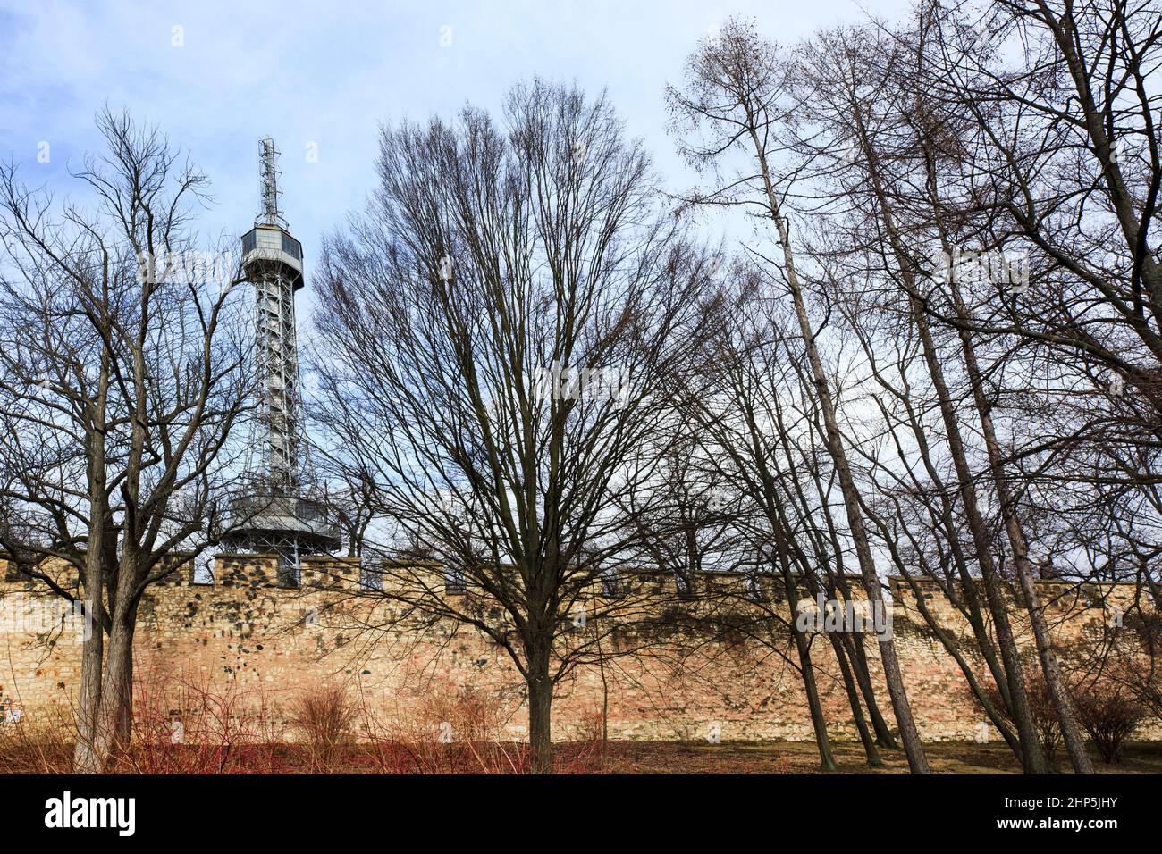 Petrin Lookout Tower from the ground rising above the crenellated walls of Petrin park in winter with bare trees Prague, Czech Republic Stock Photo
