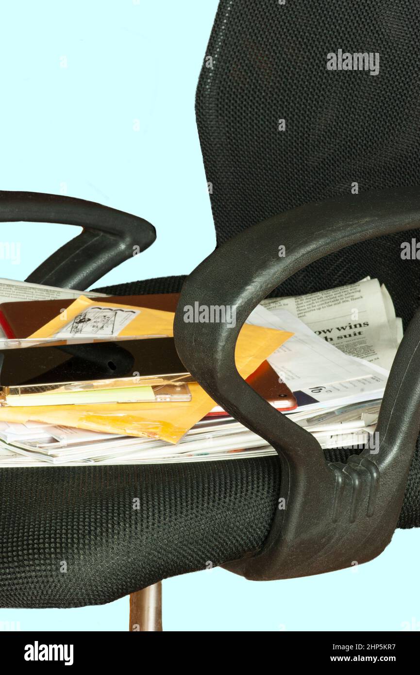 Paperwork on office chair; mail, phone, tablet, envelopes, newspapers indicating work overload, not being able to sit down. Need to hire someone. Stock Photo