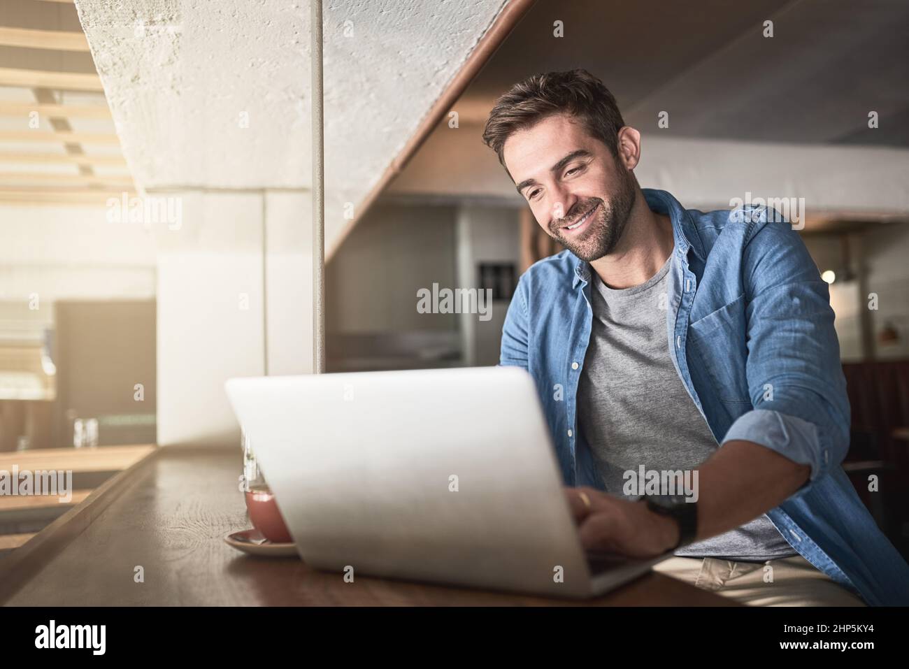 For productivity, just log in. Shot of a handsome young man using a laptop in a coffee shop. Stock Photo
