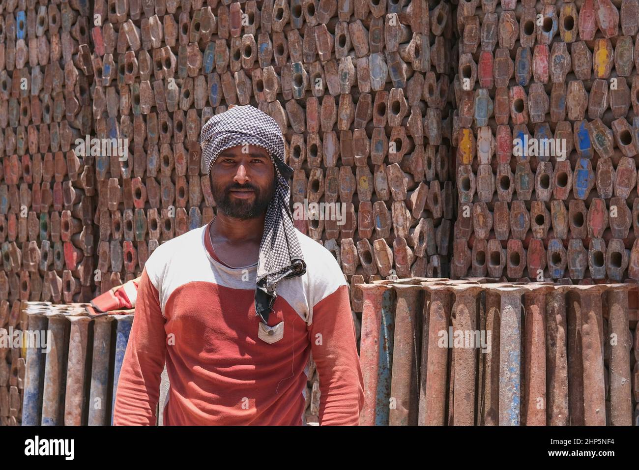 Selective focus at face of middle eastern laborer wearing muslim male headdress, working for scrap metal supply warehouse for recycling. Abu Dhabi,UAE Stock Photo