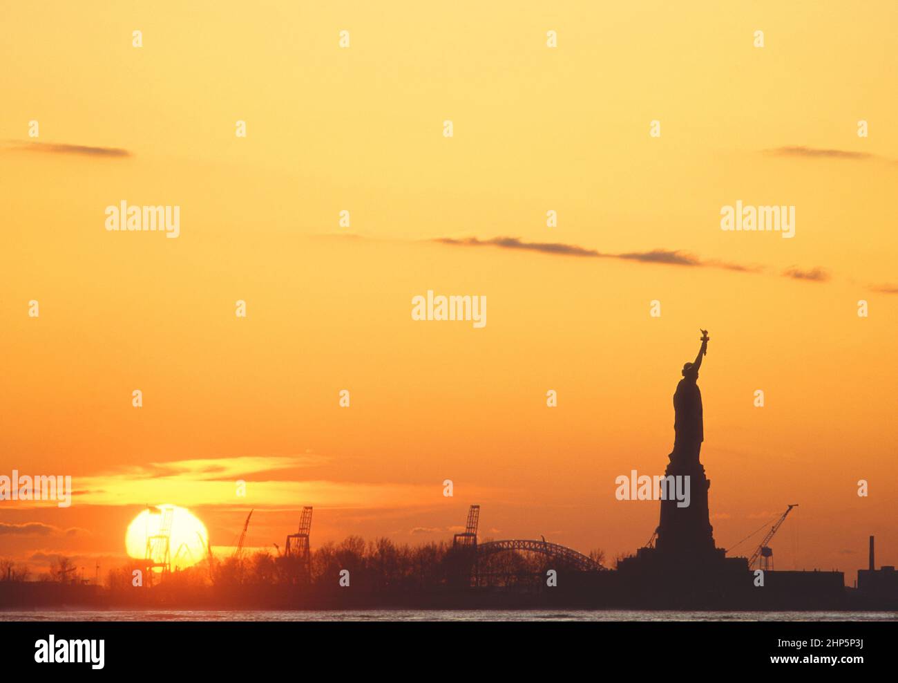 Statue of Liberty at sunset. New York Harbor setting sun. American dream landmark monument on Liberty Island. Immigration in United States of America. Stock Photo