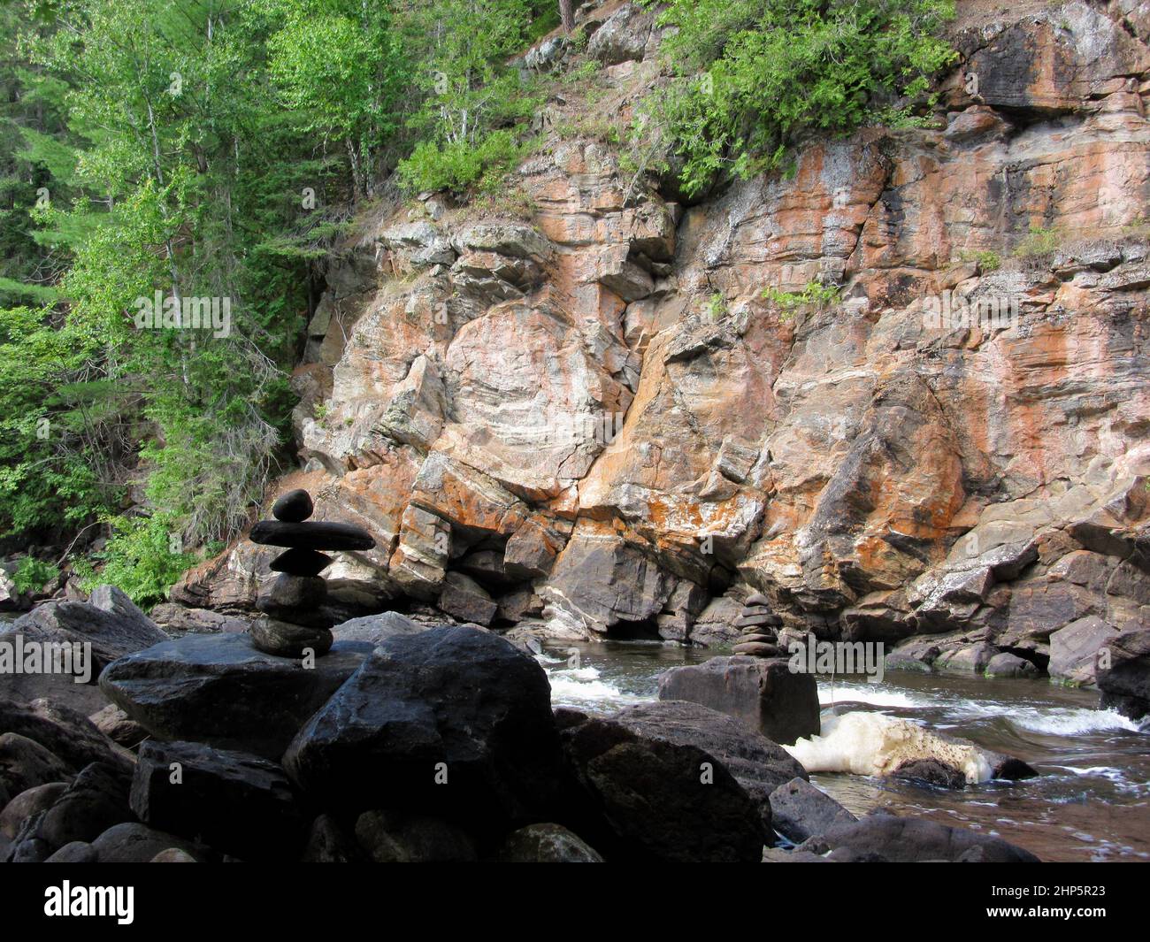 Bright red bedrock cliffs along the Madawaska River during Summer Stock Photo