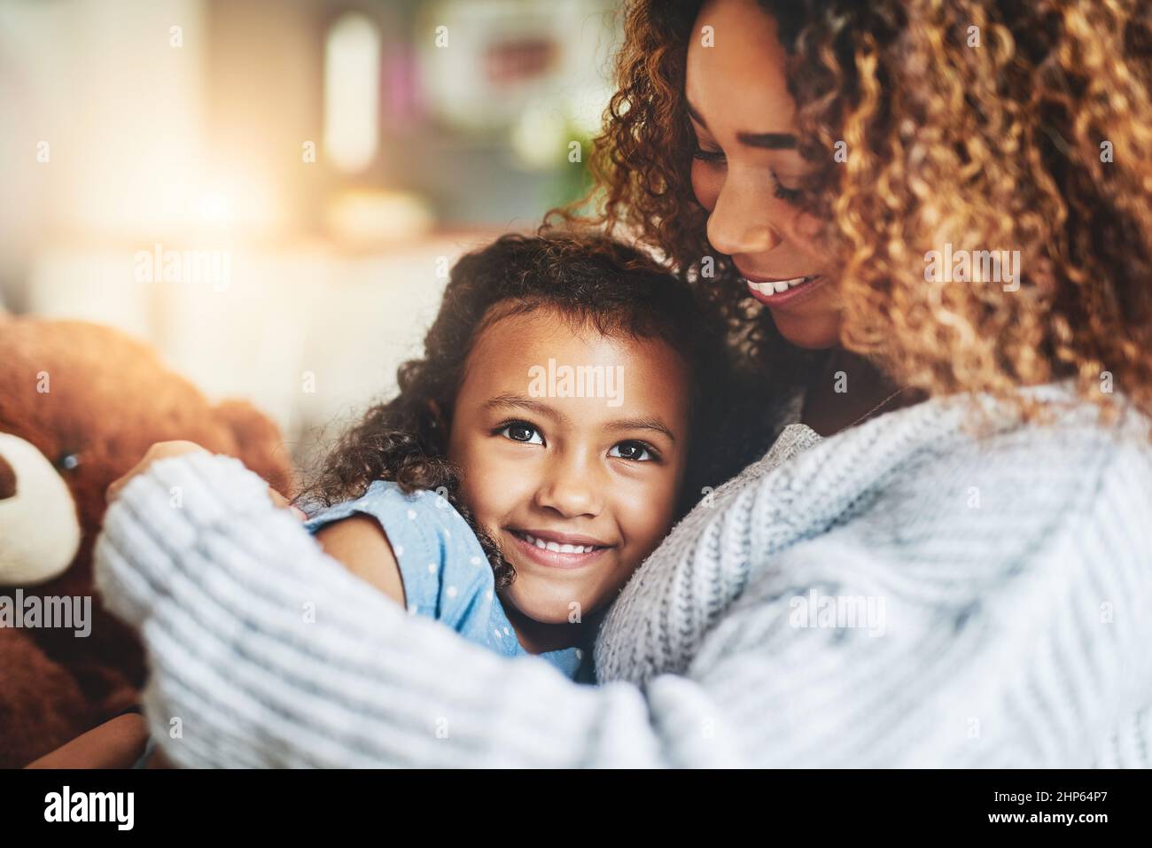 Mom hugs, nothing quite like them. Shot of an adorable little girl and her mother in a warm embrace at home. Stock Photo