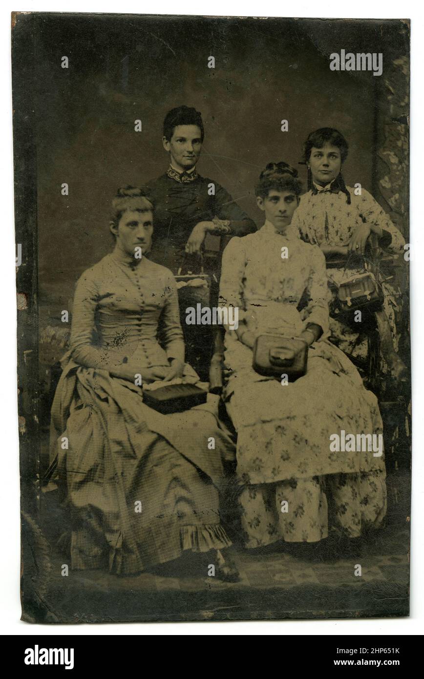Antique circa 1860 tintype photograph, a studio image of four women with pocketbooks. Location unknown, USA. SOURCE: ORIGINAL TINTYPE Stock Photo