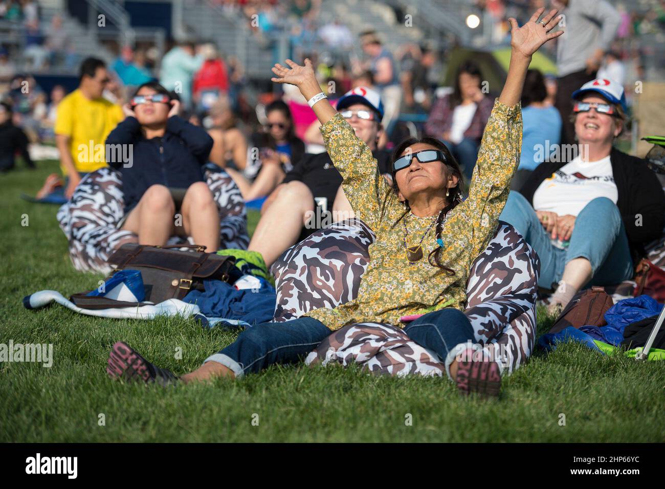 People are seen as they watch a total solar eclipse through protective glasses in Madras, Oregon on Monday, Aug. 21, 2017 Stock Photo