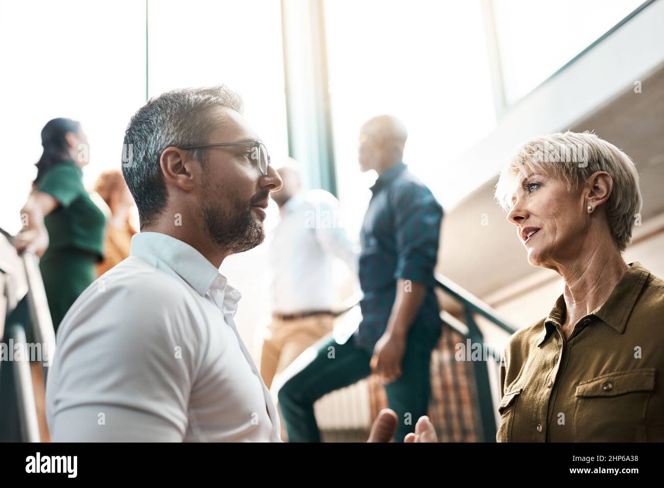 Exchanging some business advice. Shot of two businesspeople talking to each other while standing on a stairwell. Stock Photo