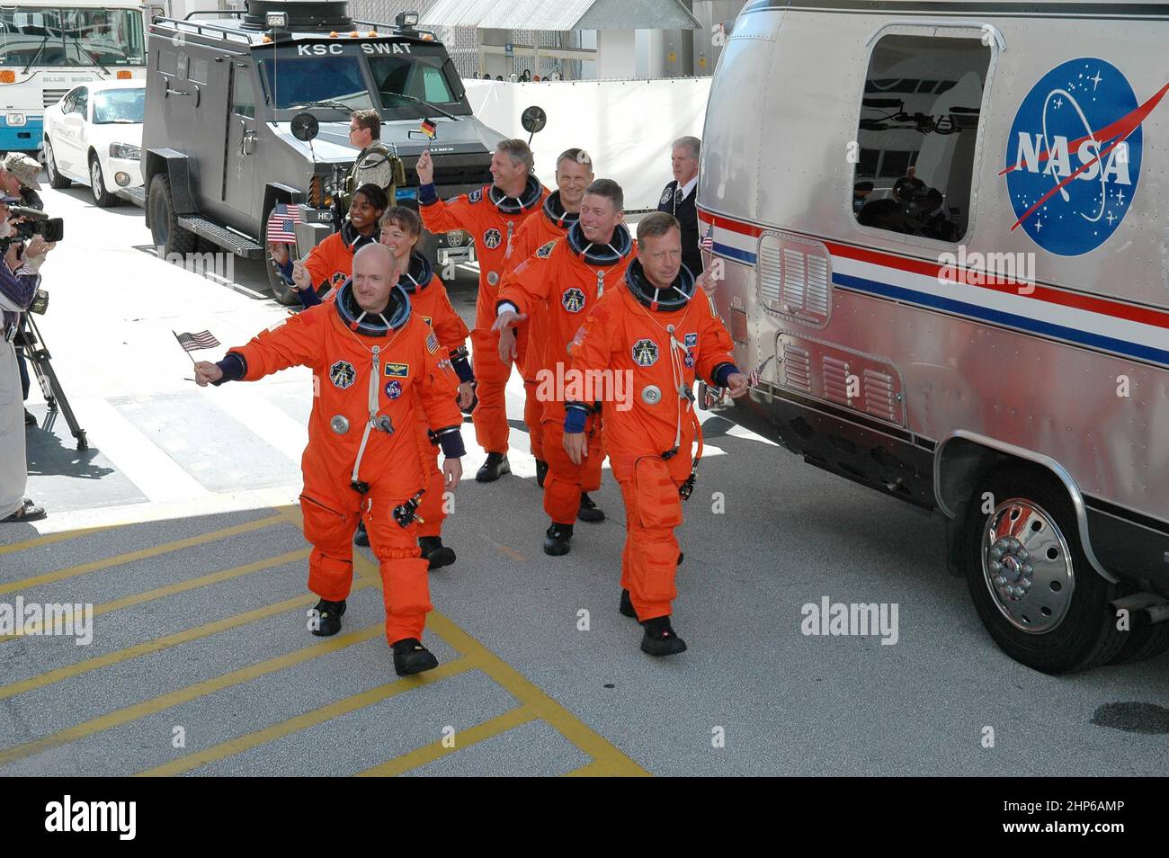 Waving flags for the Fourth of July, the STS-121 crew heads for the Astrovan and the ride to Launch Pad 39B for a third launch attempt. Leading the way are Pilot Mark Kelly (left) and Commander Steven Lindsey (right). Behind them are, left and right, Mission Specialists (second row) Lisa Nowak and Michael Fossum; (third row) Stephanie Wilson and Piers Sellers; and (at the rear) Thomas Reiter, who represents the European Space Agency Stock Photo