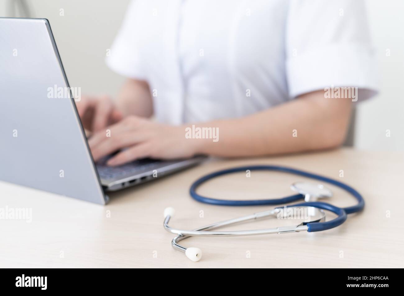 Unrecognizable female doctor in uniform uses a laptop. Faceless medical ...