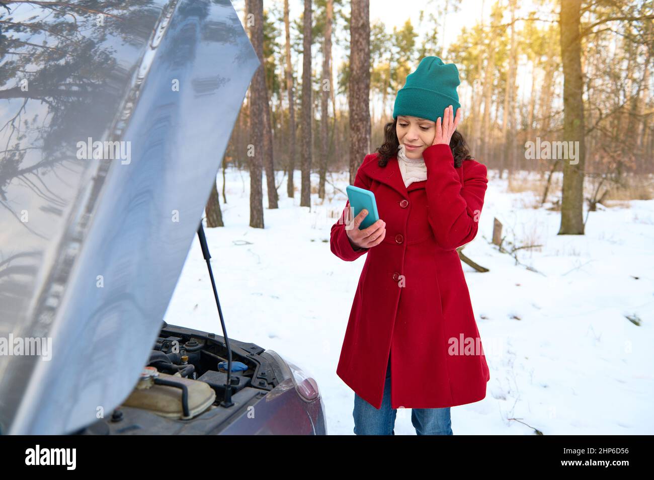 Stunned female driver with hand on temple calling tow truck or roadside ...