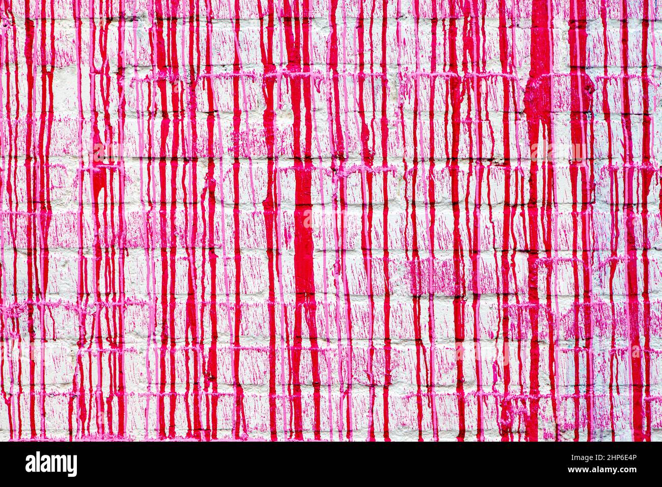 Red paint drips on a white brick wall abstract grunge color texture background Stock Photo