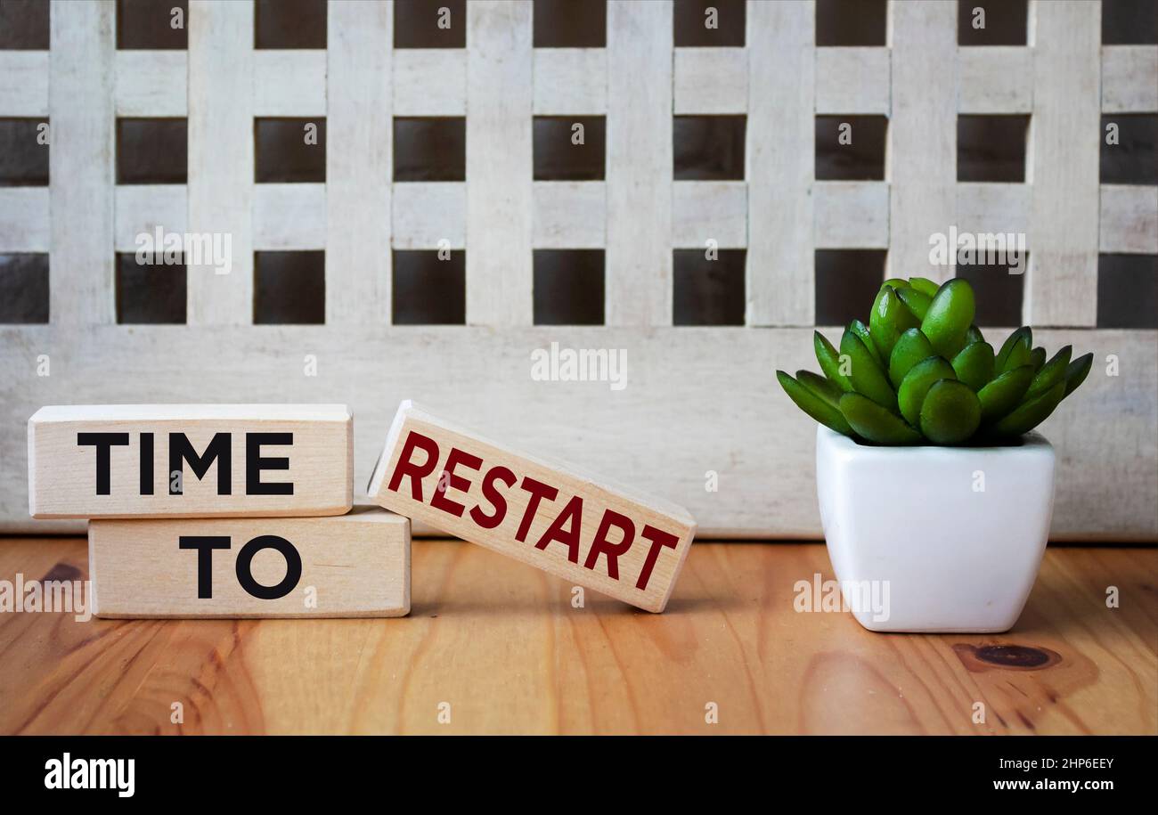 On a wooden background three wooden blocks with the text TIME TO RESTART Stock Photo