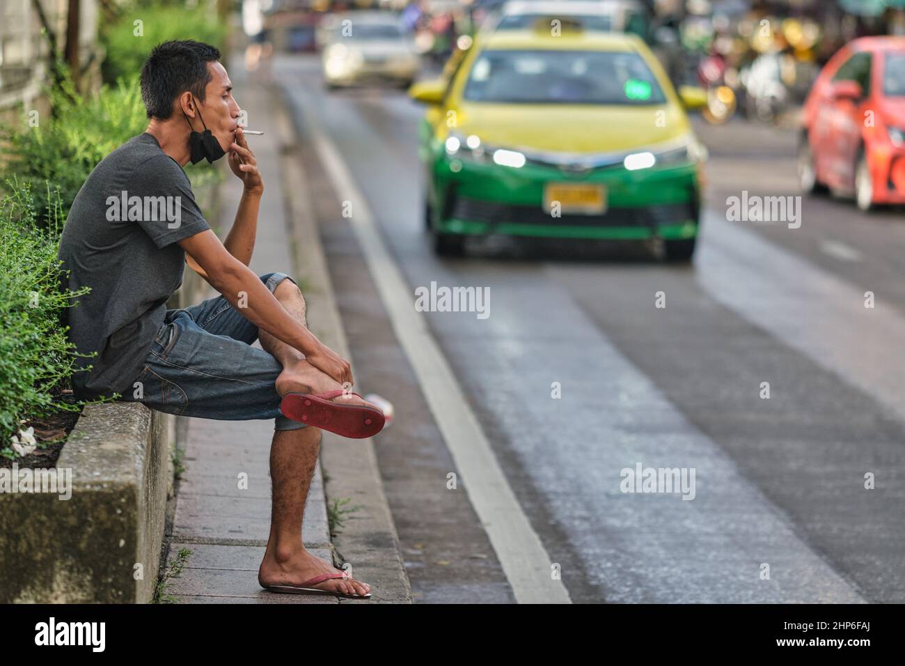 An employee of a market in Bangkok, Thailand, enjoying a moment of rest smoking his cigarette Stock Photo