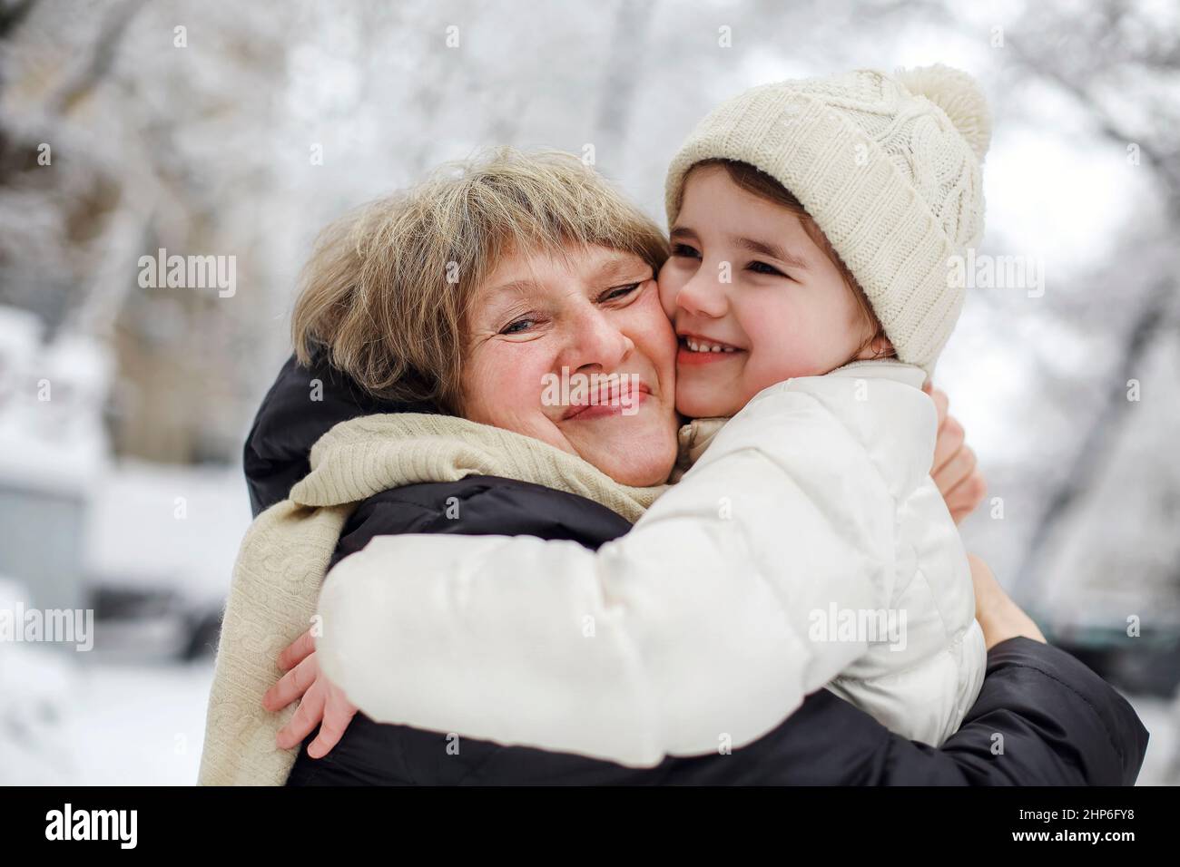 Loving grandmother with little girl granddaughter on snowy weather ...