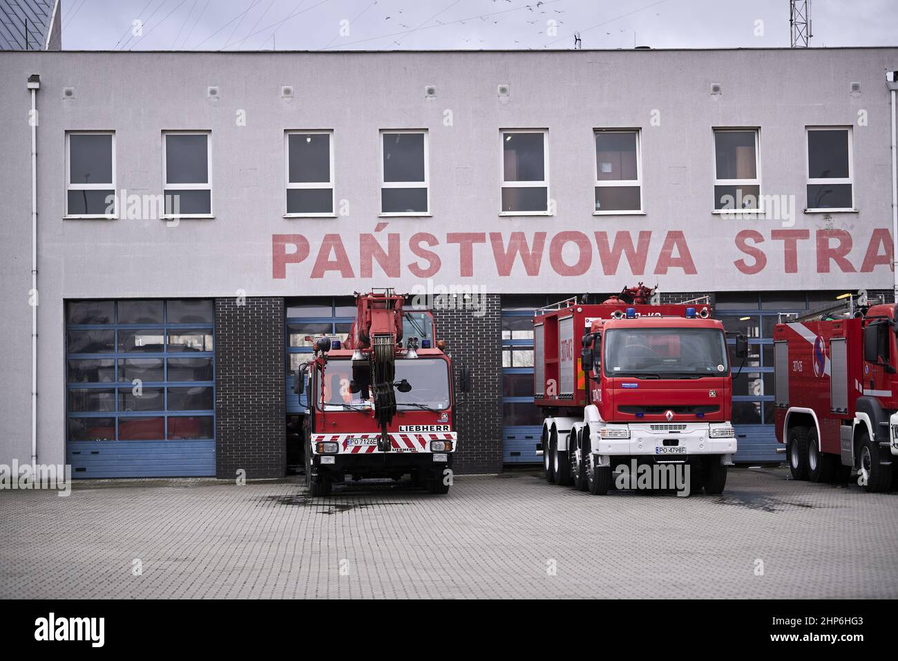 Row of parked fire trucks by a fire department station