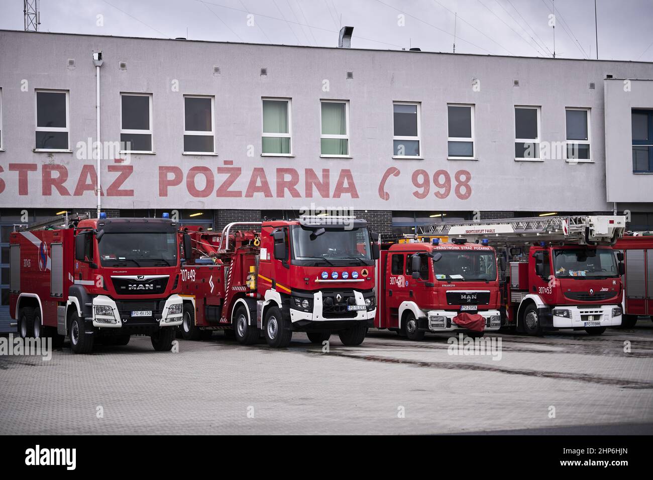 Row of parked fire trucks by a fire department station