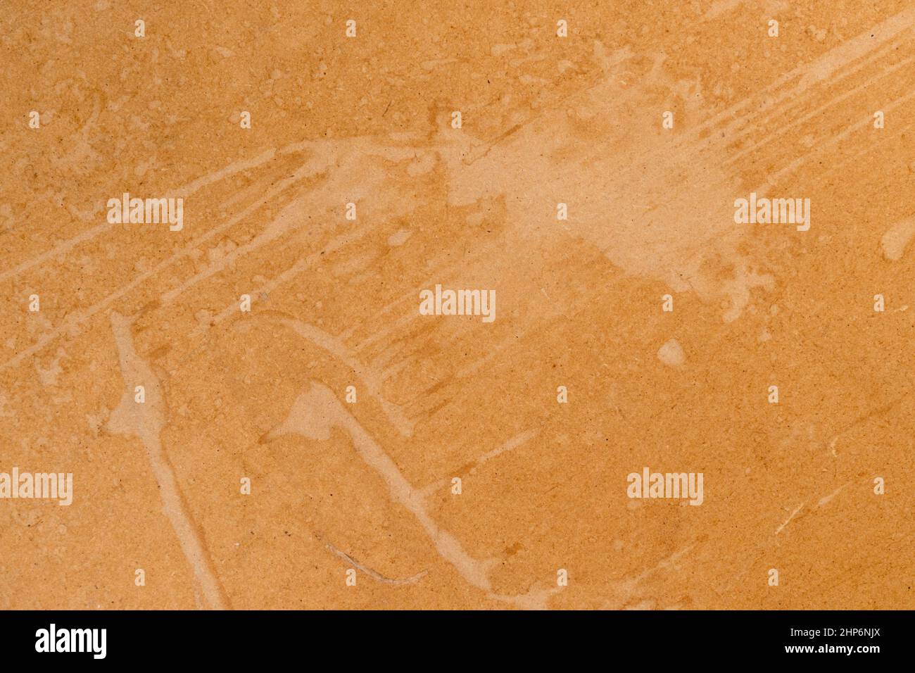 Smudges on a pressed brown rough paper. Distressed cardboard parchment. Abstract background. Dirty brush stroke close up. Copy space Stock Photo
