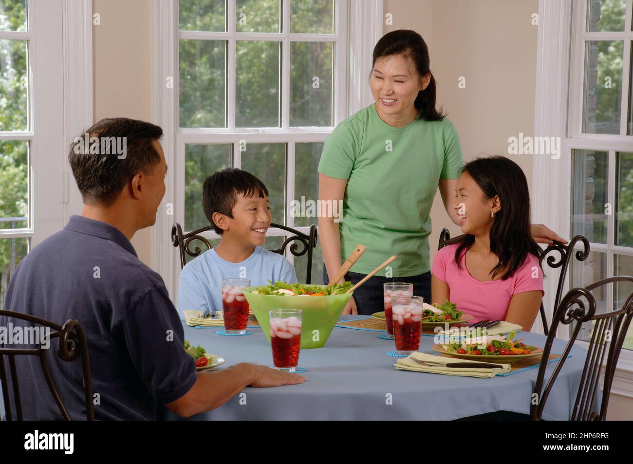 An Asian Family (adult male and female and two adolescents, male and female) are gathered around a table and eating ca.  25 July 2007 Stock Photo