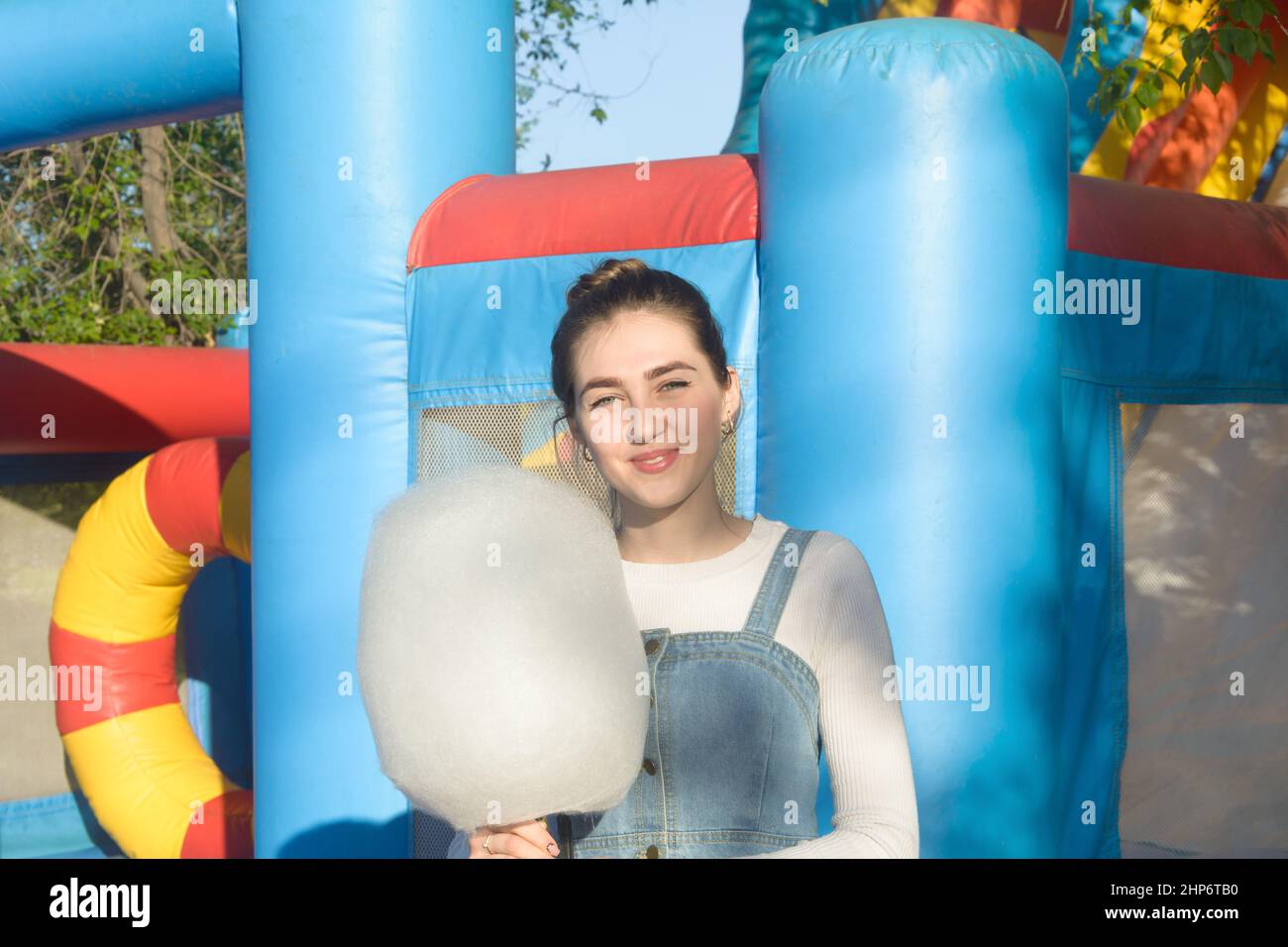 Happy young woman with cotton candy in an amusement park in summer. Stock Photo