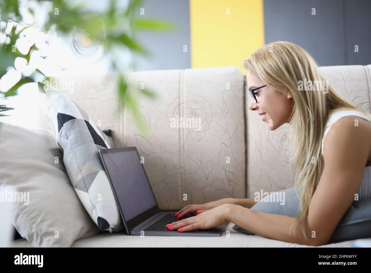 Woman with laptop at home lying on the couch Stock Photo
