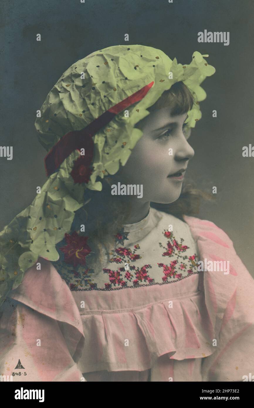 Beautiful little girl wears rural clothes  .Vintage hand-tinted photograph - post card of early of 20 century Stock Photo