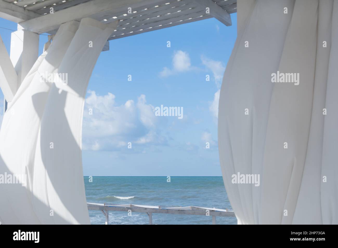 White summer terrace or veranda with transparent curtains. Sea or ocean view. Blurred background, selective focus. Stock Photo