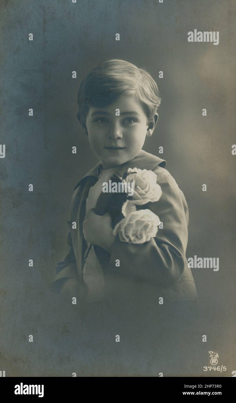 Attractive little  boy  with a bouquet of flowers. Black and white photography.  Retro postcard of early 20 century Stock Photo