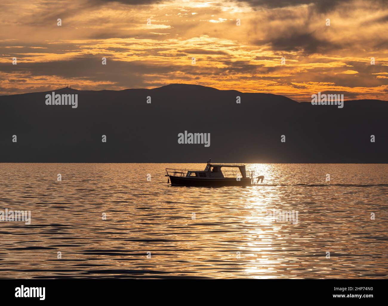 small tourist boat sails on a lake at sunset Stock Photo - Alamy