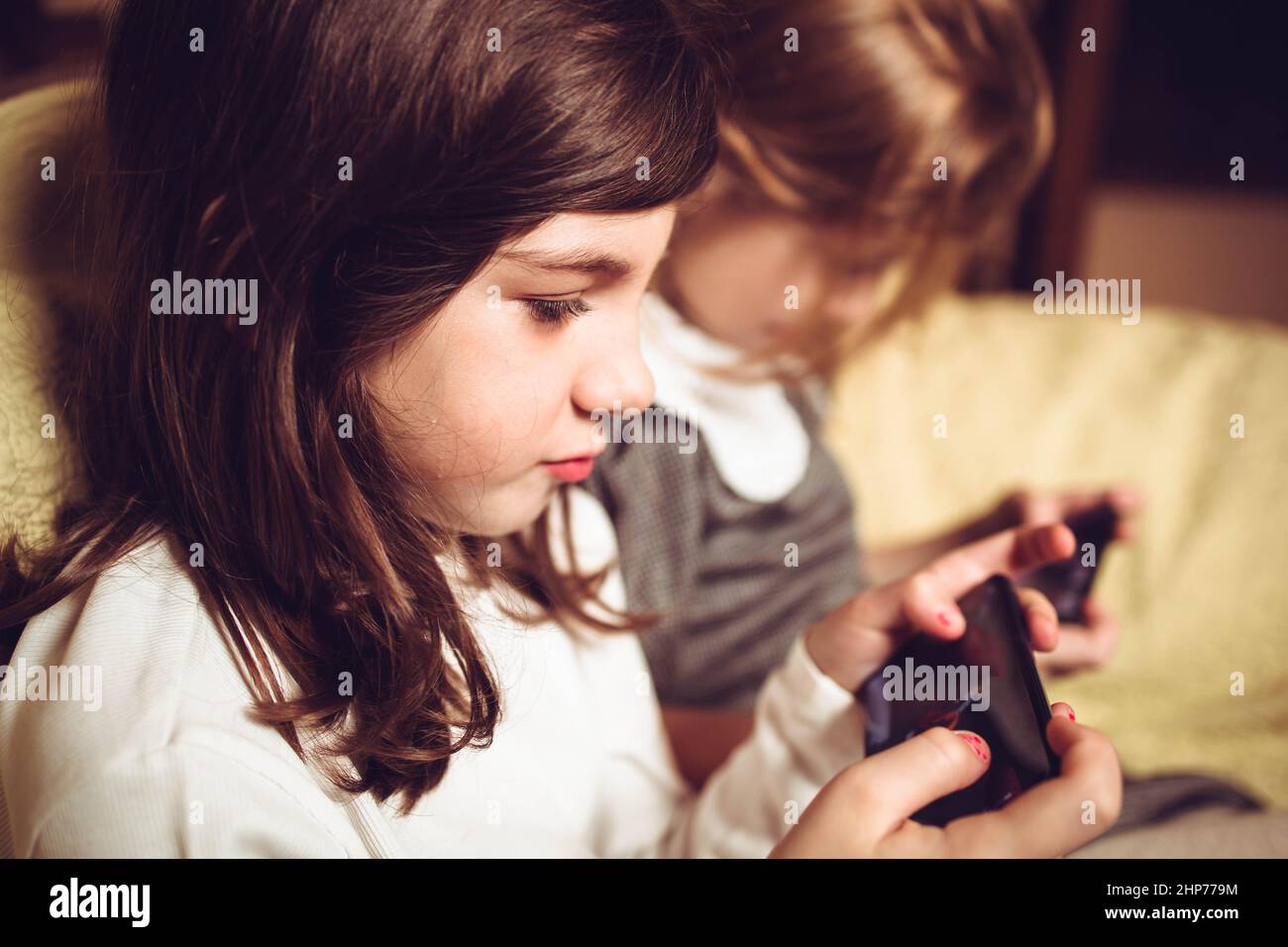 Little girls playing games on their mobile phones Stock Photo