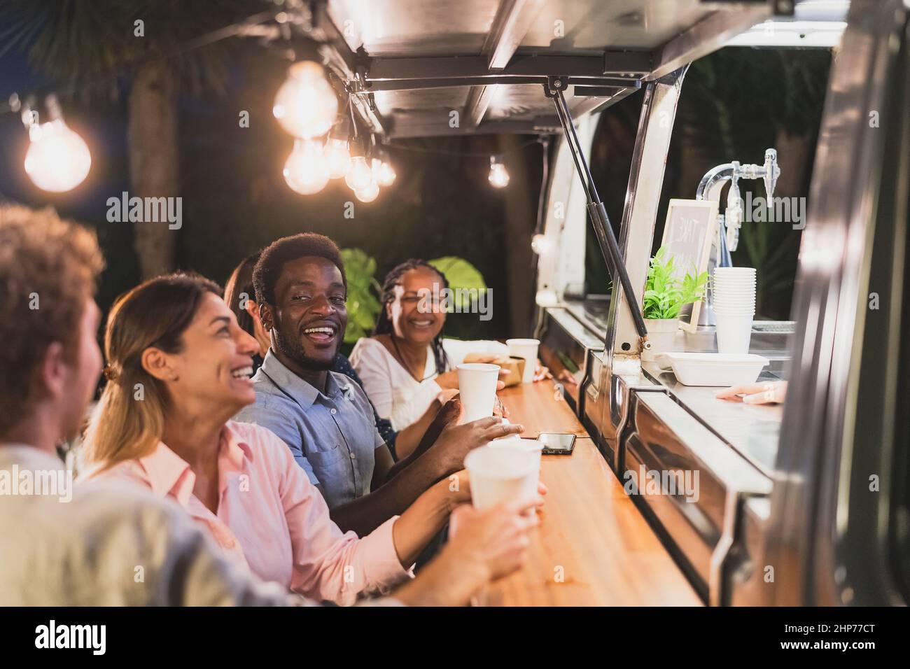 Happy multiracial people buying meal from food truck kitchen - Modern business and take away concept Stock Photo