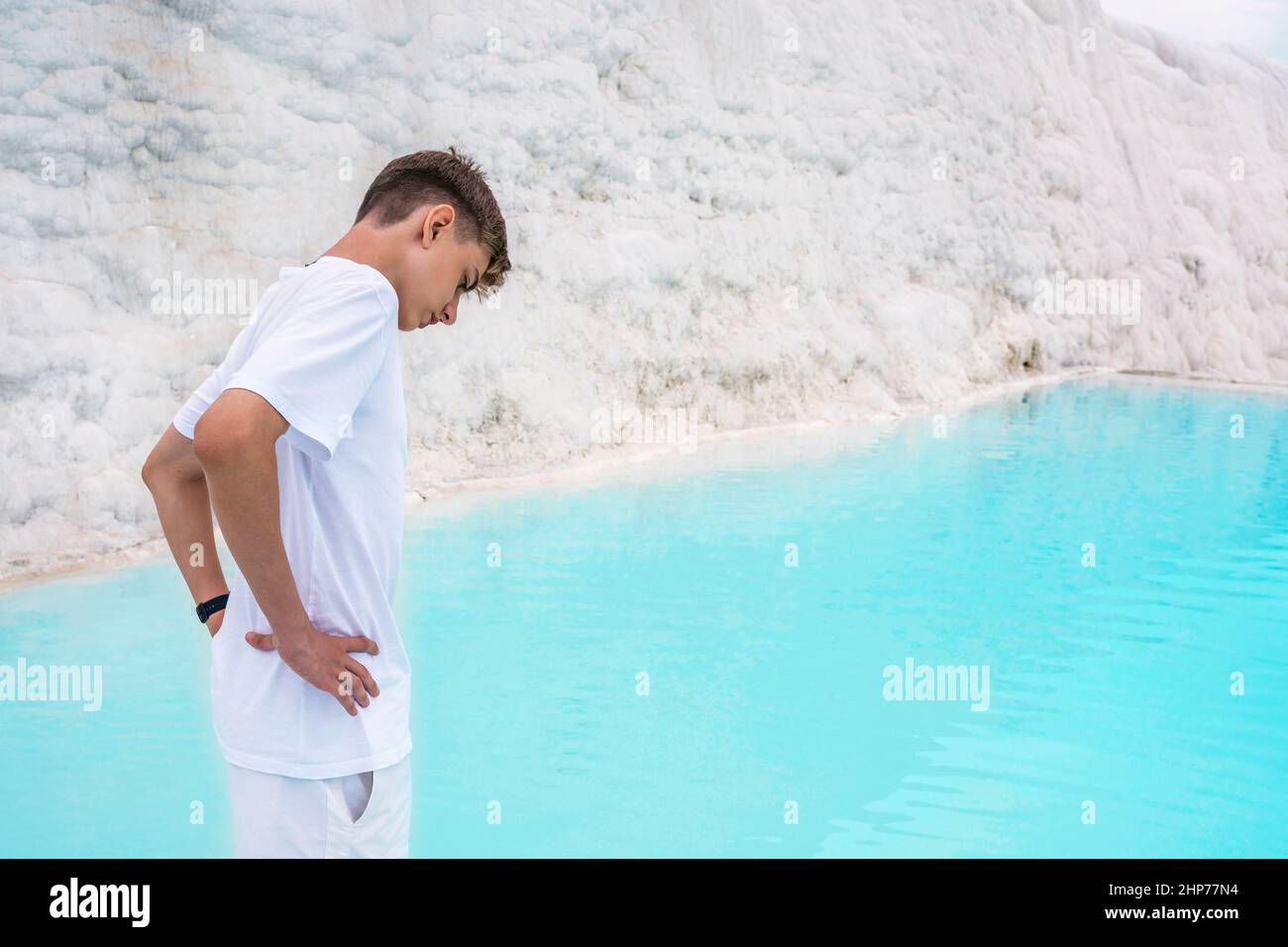 Cotton castle in southwestern Turkey, teenager in white tshirt and shorts, natural pool Pamukkale Stock Photo