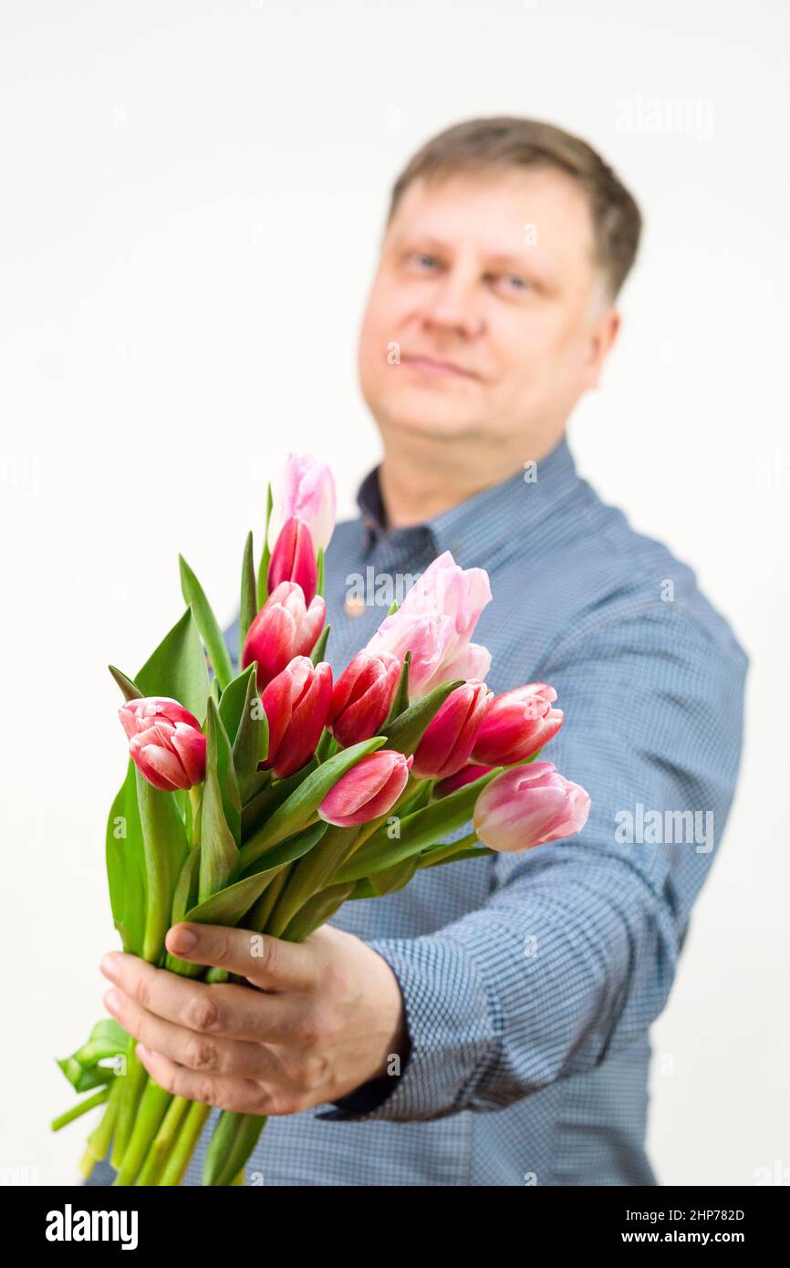 An adult male blonde holds out a bouquet of bright fragrant tulips ...