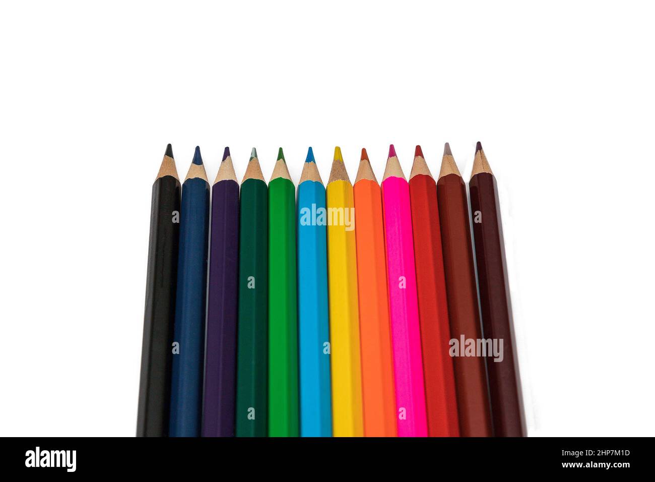Clipped colorful crayons lined up side by side on white background