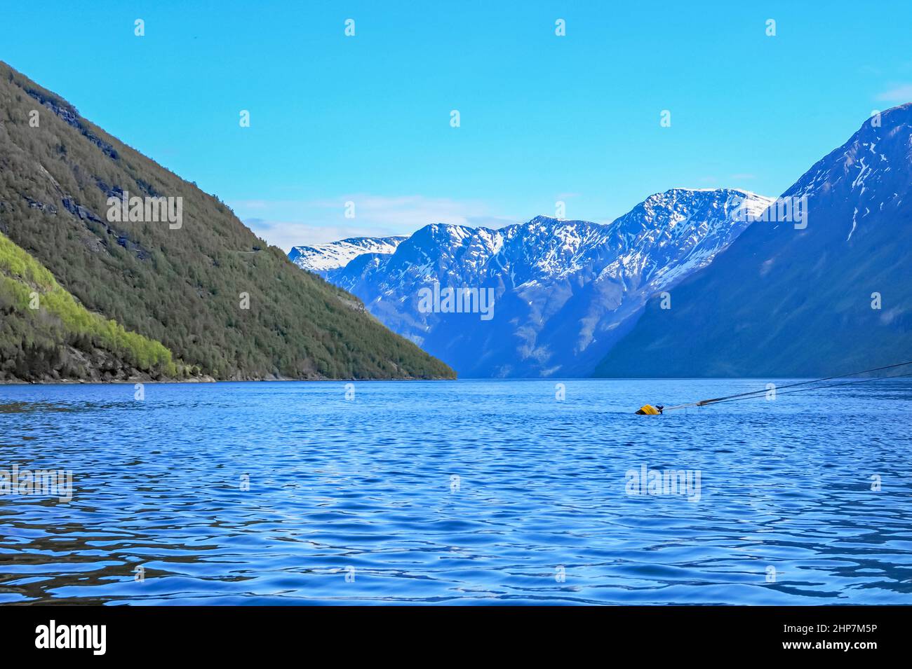 A view along the fjord over the blue waters to the snow capped mountains Stock Photo