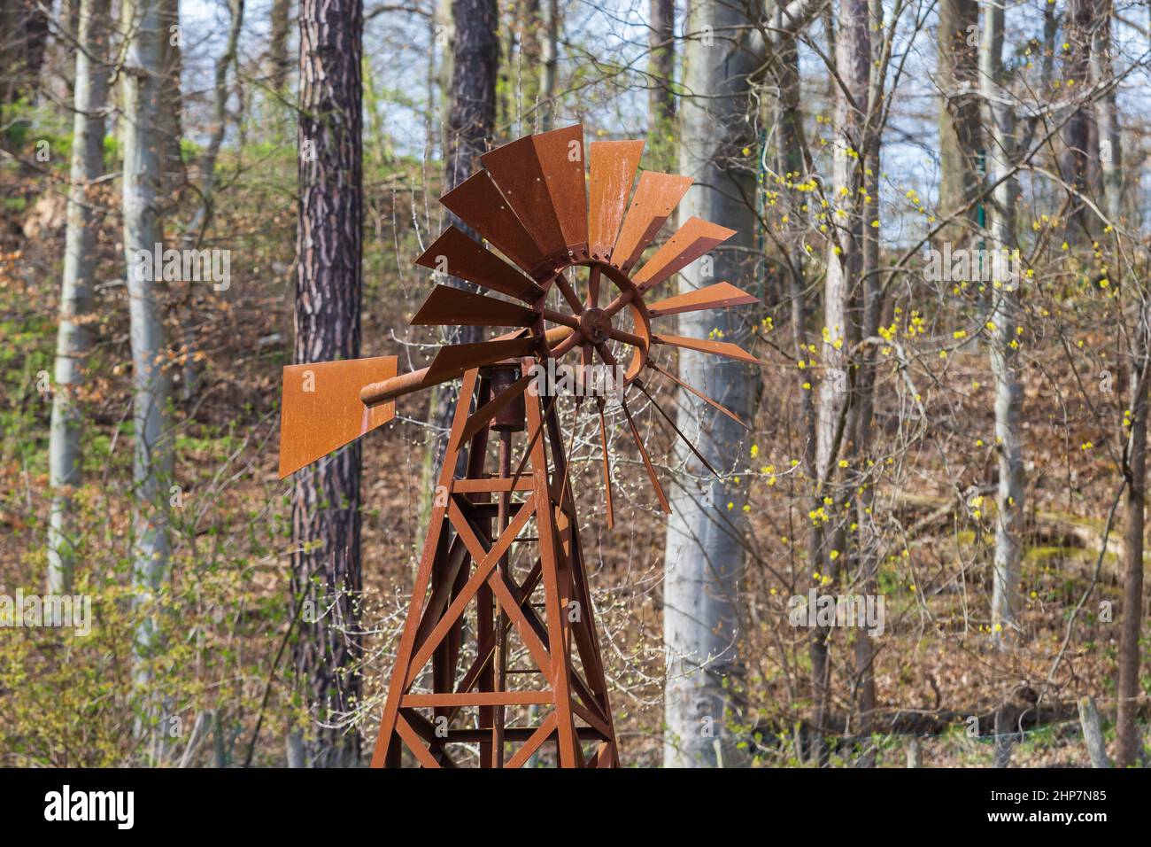 Old metal rusty pinwheel near the forest. Stock Photo
