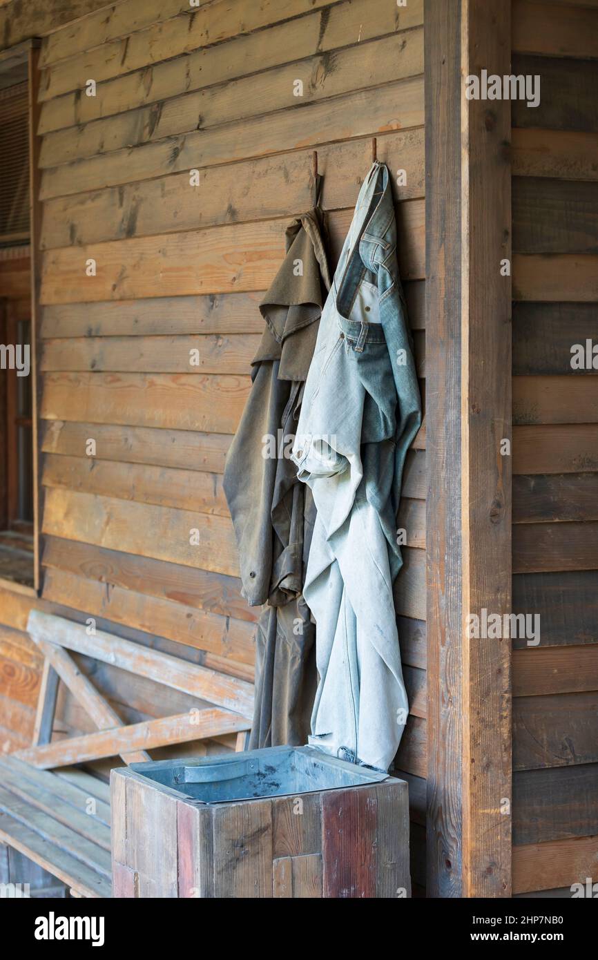 Pants and coat hanging on a hanger on a wooden wall of the house. Stock Photo