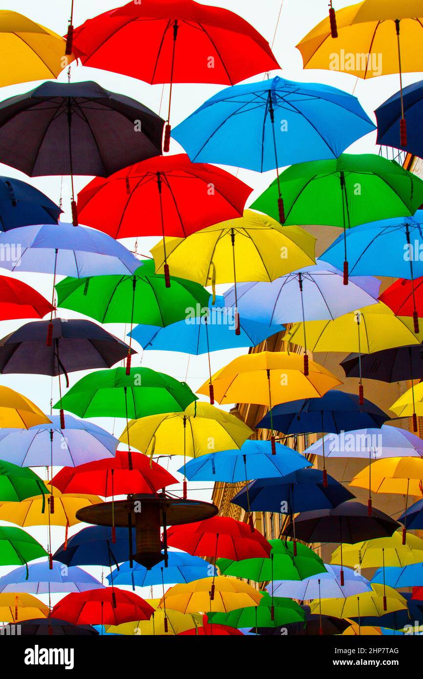 Different colored umbrellas hanging open above the street in the air. Stock Photo