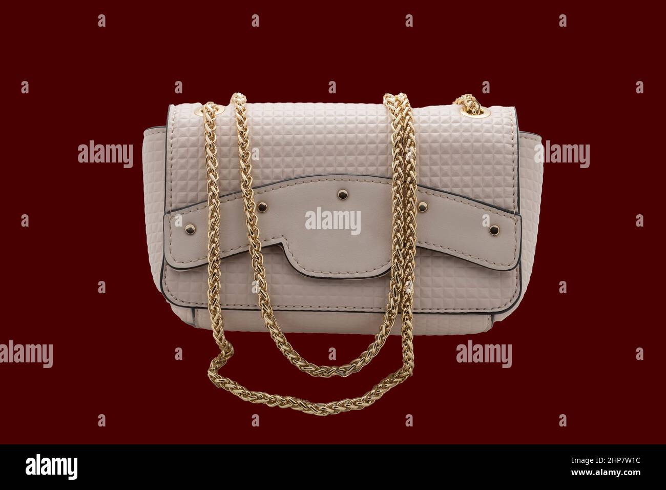 Small women's beige handbag with a gold chain. Photo on a dark background. Stock Photo