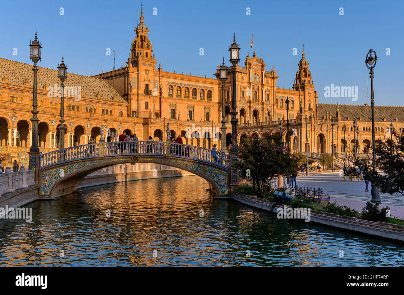 Sunset Spanish Square - Golden sunlight of Autumn sunset shines on brick and tile buildings of Spanish Square, reflecting in its canal. Seville, Spain Stock Photo