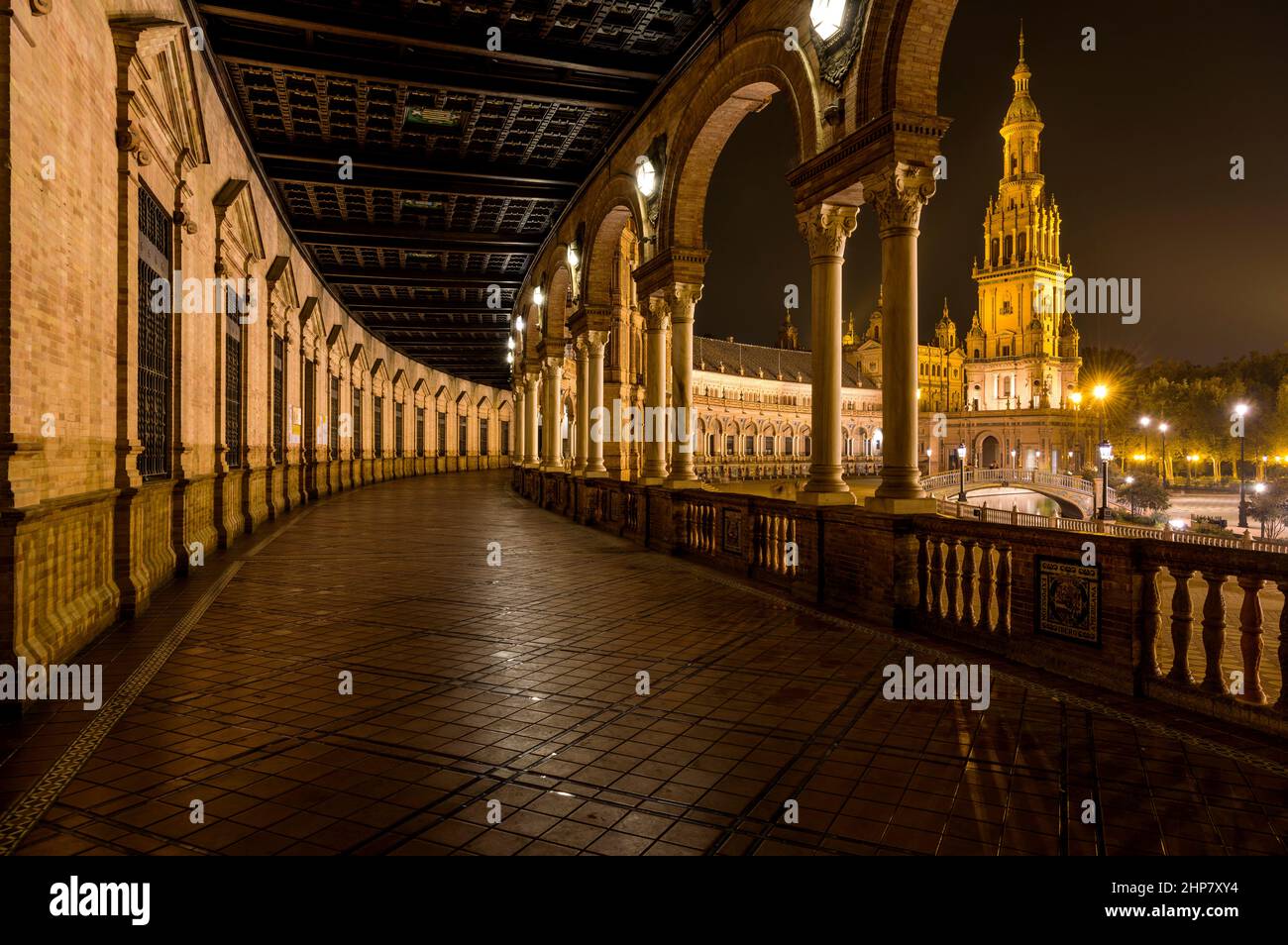 Spanish Square - Night view of the illuminated ground-level portico curving along the semi-circular brick building at Spanish Square, Seville, Spain. Stock Photo