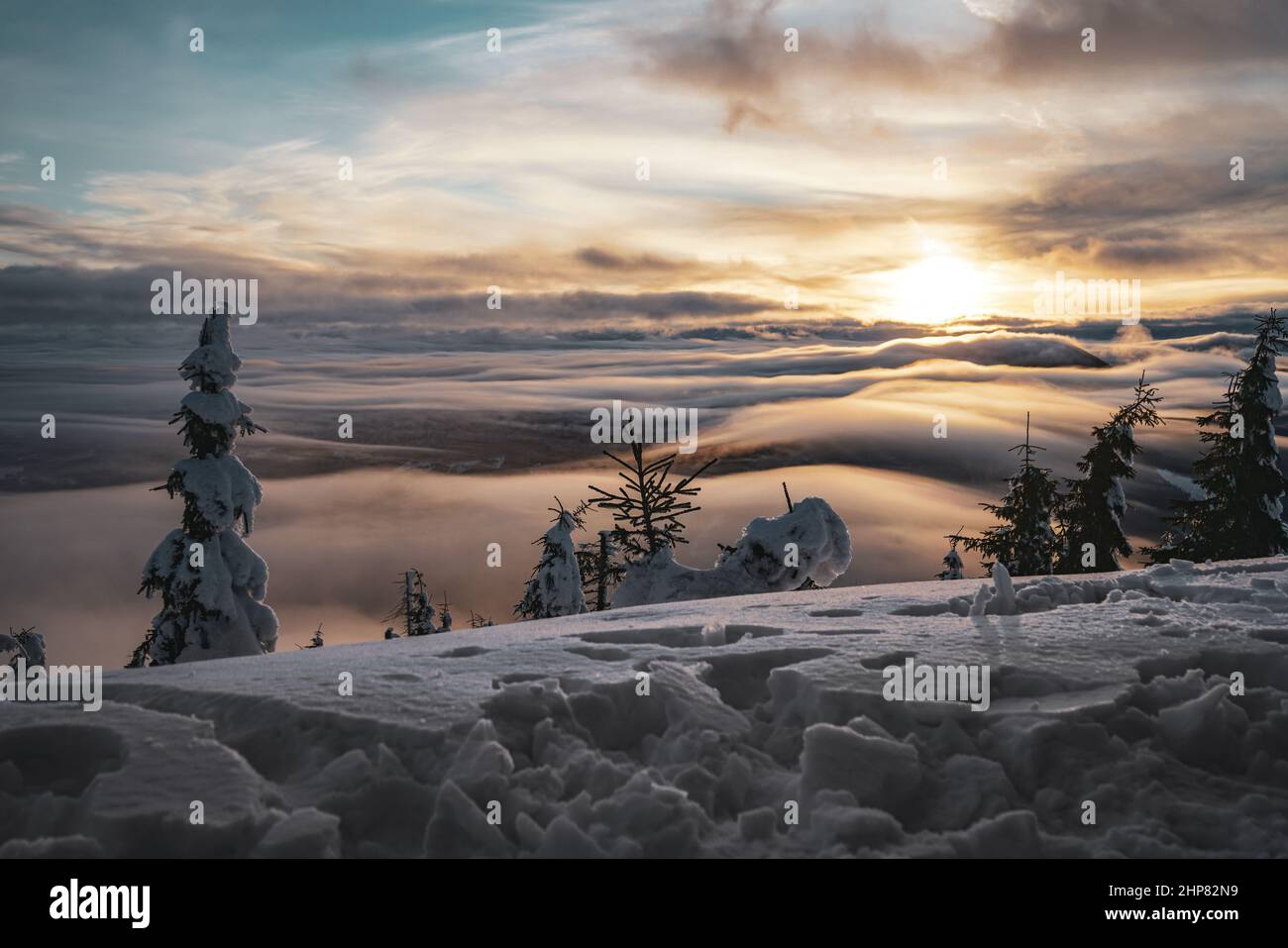 Sunset View From Top of the mountain with Trees and Low Clouds with snow in Europe Stock Photo
