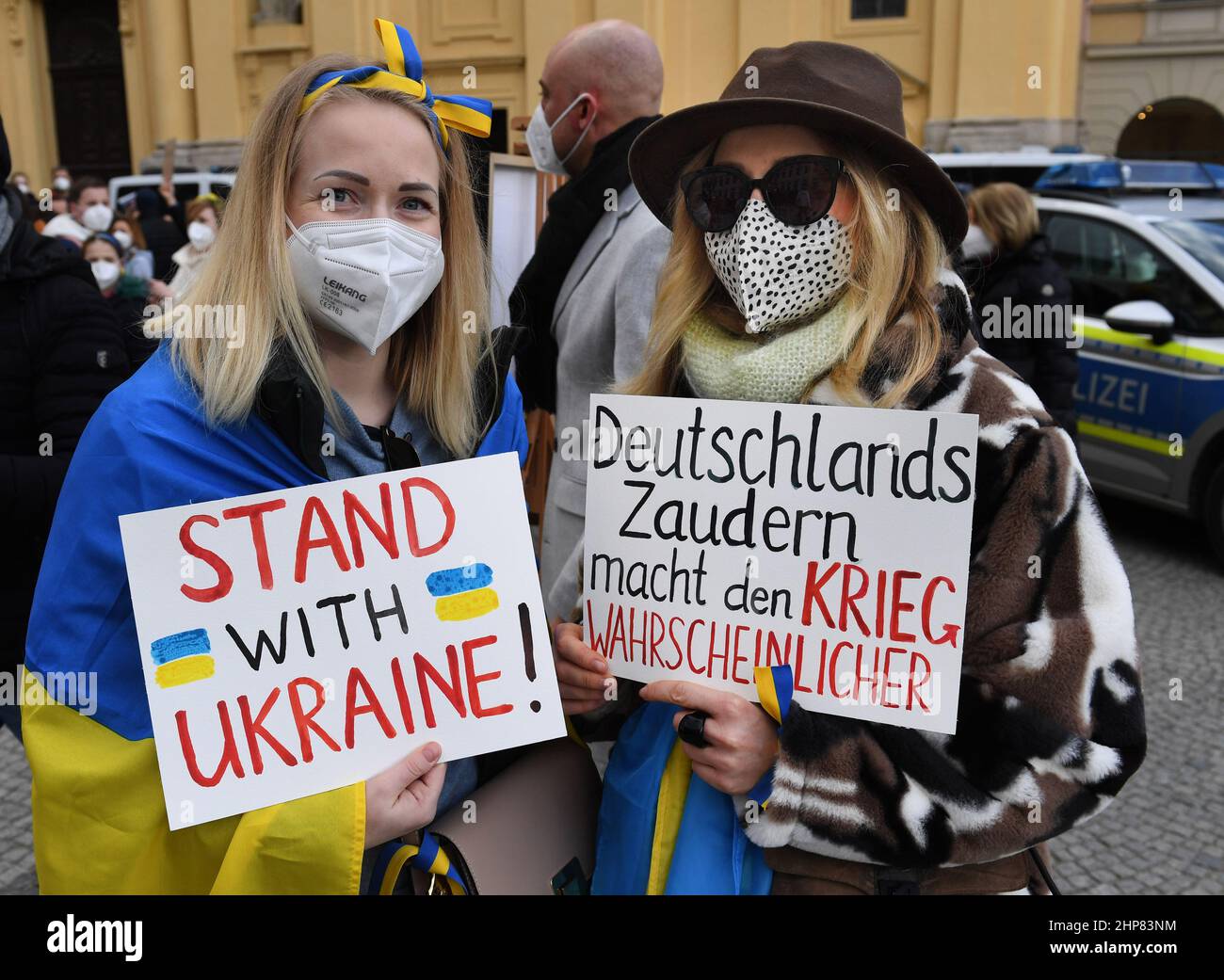 Munich, Germany. 19th Feb, 2022. Demonstrators holding placards reading 'Stand with Ukraine!' and 'Germany's dithering makes war more likely' stand at a pro-Ukraine demonstration during the security conference at Odeonsplatz. The focus of the three-day security policy forum is the Ukraine crisis. Credit: Felix Hörhager/dpa/Alamy Live News Stock Photo