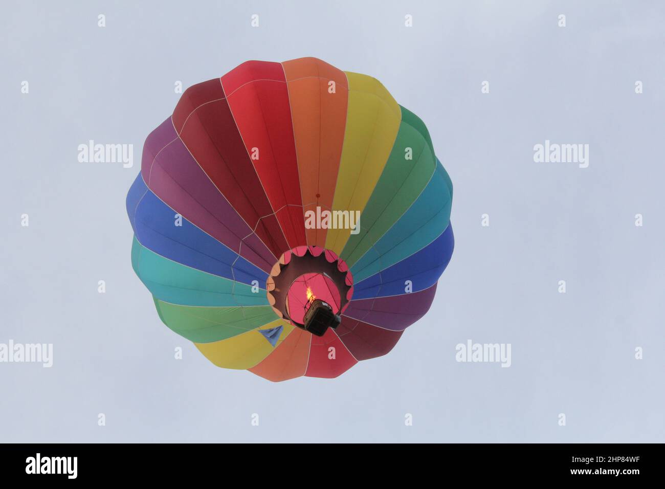 a beautiful hot air balloon with the colours of the rainbow in a light blue sky in Sint-niklaas in Belgium during the annual peace festivities Stock Photo