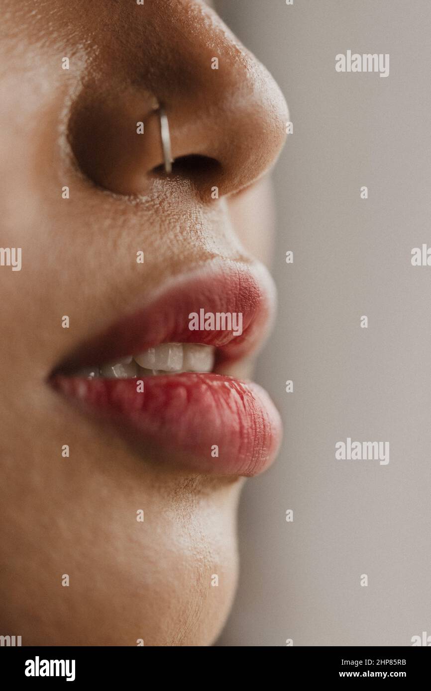 Vertical shot of a female s lips and nose with a piercing Stock